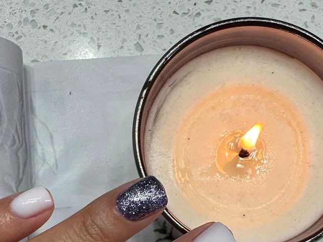 A quiet moment in the studio — a lit candle beside a freshly done glitter manicure